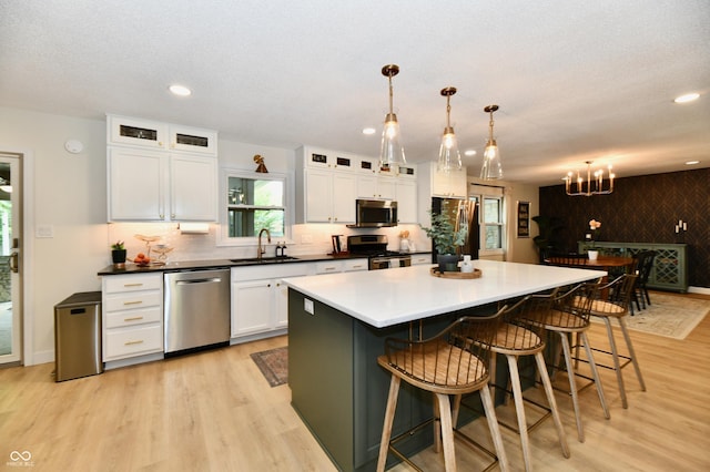 7242 Highburry Dr, Indianapolis, IN 46256 - kitchen with stainless steel appliances, light wood-style floors, white cabinets, a breakfast bar area, and recessed lighting