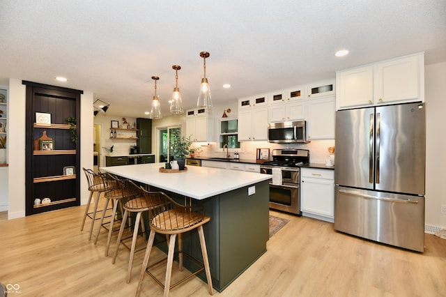 7242 Highburry Dr, Indianapolis, IN 46256 - kitchen with stainless steel appliances, white cabinets, light wood-type flooring, a center island, and glass insert cabinets