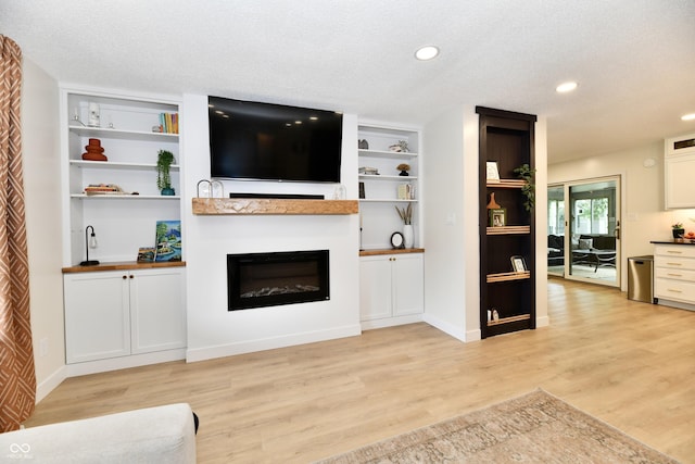 7242 Highburry Dr, Indianapolis, IN 46256 - living room with a glass covered fireplace, light wood-style flooring, built in shelves, recessed lighting, and a textured ceiling