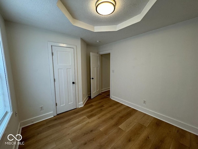 1421 S Meridian St, Indianapolis, IN 46225 - unfurnished bedroom featuring wood finished floors, baseboards, a raised ceiling, and a textured ceiling