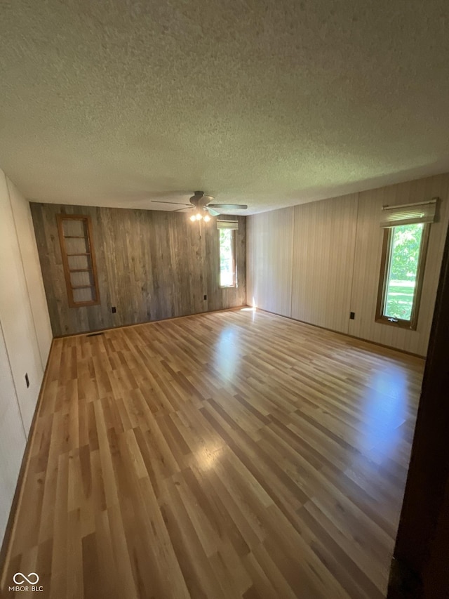 6758 S US Highway 63, Hillsdale, IN 47854 - spare room featuring light wood-style floors, a textured ceiling, wooden walls, and a ceiling fan