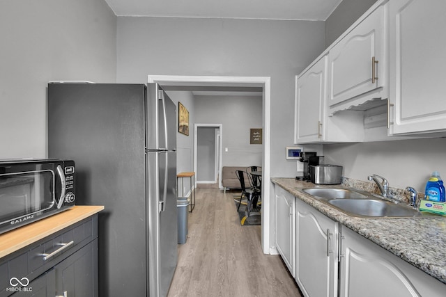 1141 N Shadeland Ave, Indianapolis, IN 46219 - kitchen with freestanding refrigerator, black microwave, light wood-style floors, white cabinets, and light countertops