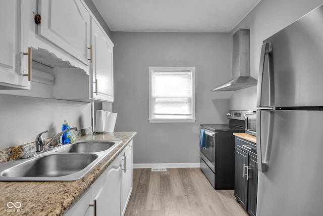 1141 N Shadeland Ave, Indianapolis, IN 46219 - kitchen featuring stainless steel appliances, wall chimney range hood, light wood-style floors, light countertops, and white cabinetry
