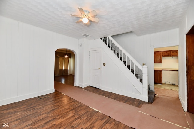 1346 W 27th St, Indianapolis, IN 46208 - empty room featuring ceiling fan, wood finished floors, baseboards, stairs, and arched walkways