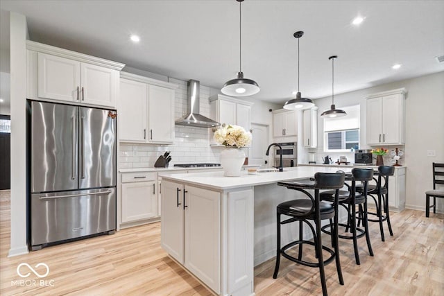 7154 Covington St, Lebanon, IN 46052 - kitchen featuring stainless steel appliances, wall chimney exhaust hood, backsplash, light wood-type flooring, and white cabinetry