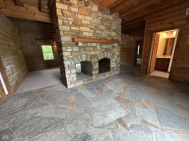 2858 N Stout Rd, Liberty, IN 47353 - unfurnished living room featuring wooden walls, an outdoor stone fireplace, stone flooring, and wooden ceiling with exposed beams
