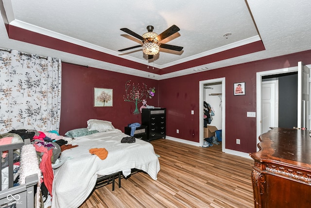 1217 Old Vines Trl, Greenwood, IN 46143 - bedroom with a tray ceiling, wood finished floors, a textured ceiling, a walk in closet, and a ceiling fan