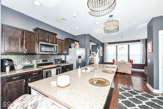 1217 Old Vines Trl, Greenwood, IN 46143 - kitchen featuring stainless steel appliances, dark brown cabinetry, a center island with sink, dark wood-style floors, and backsplash