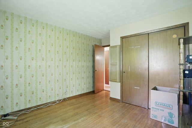 1914 S Avon Ave, Avon, IN 46123 - unfurnished bedroom featuring wood finished floors, a closet, and wallpapered walls