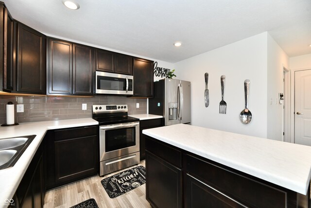 6883 Honeysuckle Way, Pendleton, IN 46064 - kitchen featuring appliances with stainless steel finishes, light countertops, light wood-type flooring, tasteful backsplash, and a sink