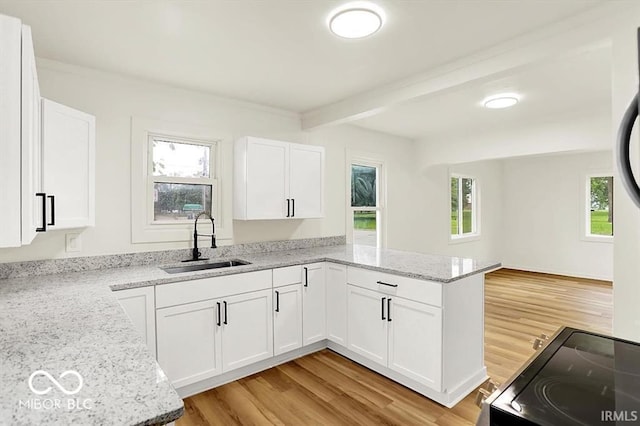 701 E Memorial Dr, Muncie, IN 47302 - kitchen with a sink, a peninsula, light wood-style flooring, light stone countertops, and beam ceiling
