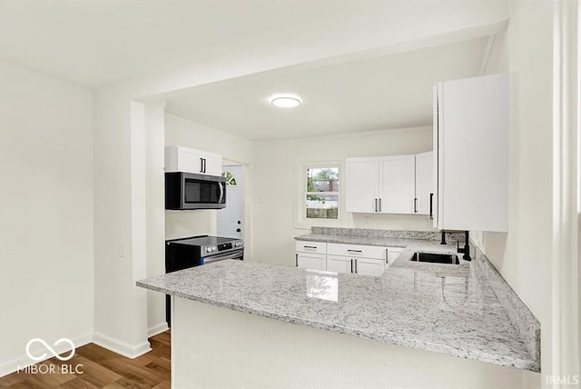 701 E Memorial Dr, Muncie, IN 47302 - kitchen with appliances with stainless steel finishes, a sink, light stone counters, and a peninsula