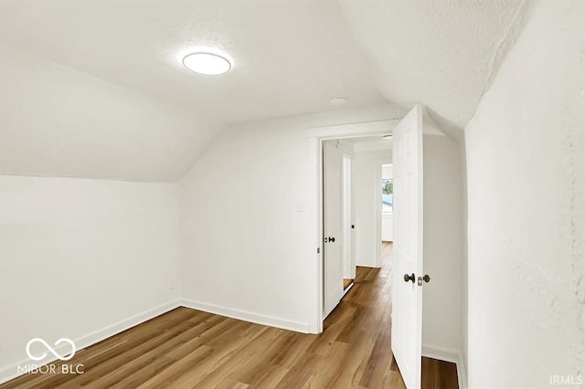 701 E Memorial Dr, Muncie, IN 47302 - additional living space with lofted ceiling, a textured ceiling, baseboards, and wood finished floors