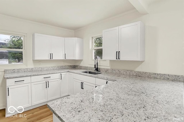 701 E Memorial Dr, Muncie, IN 47302 - kitchen featuring a sink, light stone countertops, white cabinets, light wood-style flooring, and ornamental molding