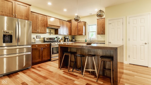 2020 N Park Ave, Indianapolis, IN 46202 - kitchen featuring stainless steel appliances, premium range hood, light wood finished floors, a kitchen breakfast bar, and a sink