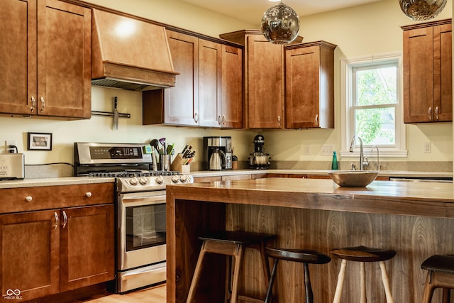 2020 N Park Ave, Indianapolis, IN 46202 - kitchen with gas stove, premium range hood, a breakfast bar, and light wood-type flooring