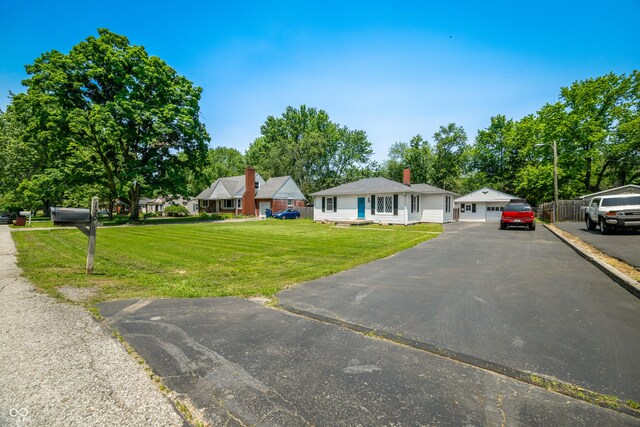 120 Hoss Rd, Indianapolis, IN 46217 - view of front of home featuring a front lawn, asphalt driveway, a chimney, a detached garage, and view of scattered trees