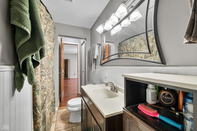 120 Hoss Rd, Indianapolis, IN 46217 - bathroom with toilet, vanity, a wainscoted wall, and tile patterned flooring