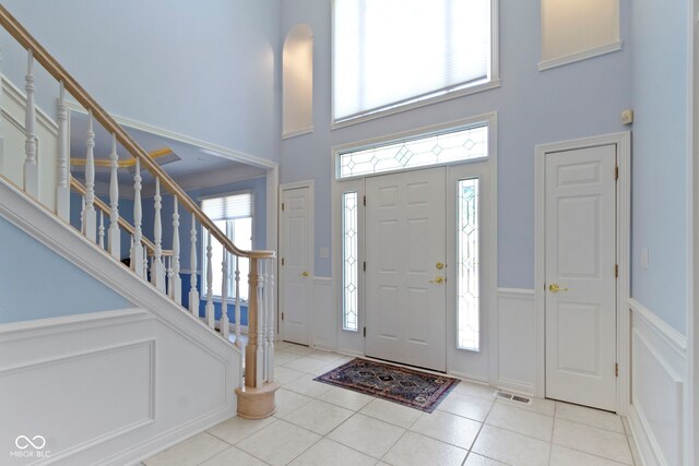 4763 Woods Edge Dr, Zionsville, IN 46077 - entrance foyer with a towering ceiling, tile patterned floors, stairway, a decorative wall, and a wainscoted wall