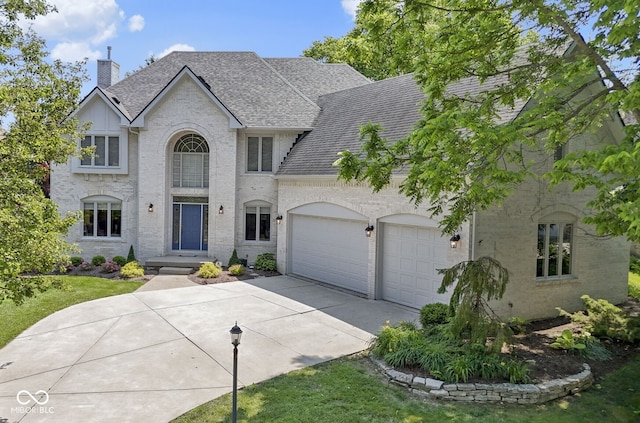 4763 Woods Edge Dr, Zionsville, IN 46077 - french country style house with driveway, a garage, roof with shingles, a chimney, and brick siding