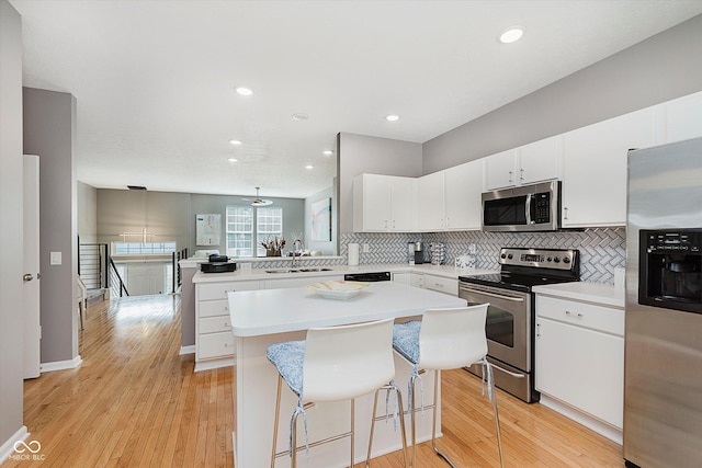 8425 Codesa Way, Indianapolis, IN 46278 - kitchen with appliances with stainless steel finishes, a peninsula, a sink, decorative backsplash, and light countertops