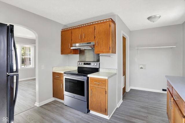 11 14th St, Franklin, IN 46131 - kitchen featuring stainless steel electric range oven, freestanding refrigerator, arched walkways, under cabinet range hood, and brown cabinets