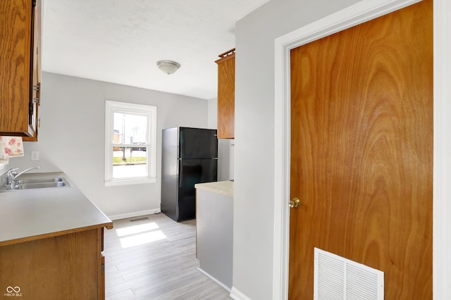 11 14th St, Franklin, IN 46131 - kitchen featuring a sink, freestanding refrigerator, baseboards, light wood-type flooring, and light countertops