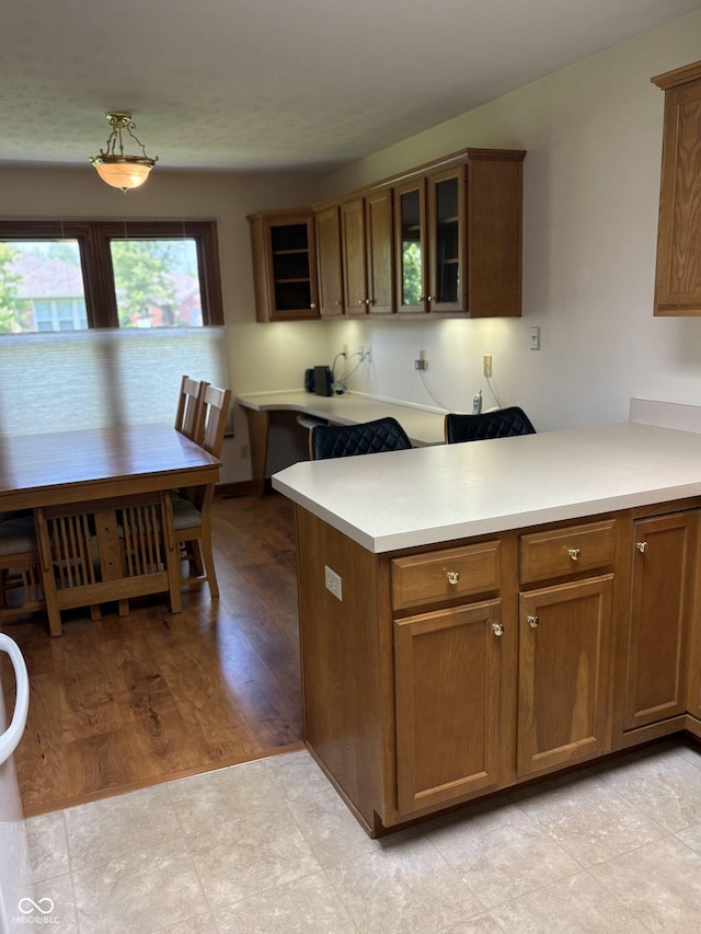 5148 Constitution Ct, Columbus, IN 47203 - kitchen featuring glass insert cabinets, light countertops, a peninsula, and brown cabinetry