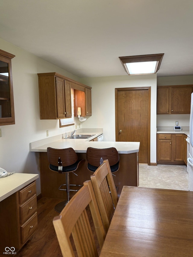 5148 Constitution Ct, Columbus, IN 47203 - kitchen with a sink, a breakfast bar area, a peninsula, light countertops, and brown cabinets