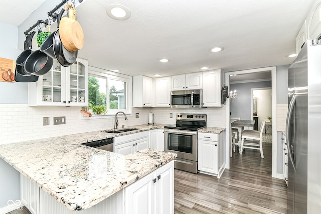 164 Wellington Pkwy, Noblesville, IN 46060 - kitchen featuring appliances with stainless steel finishes, a sink, a peninsula, glass insert cabinets, and white cabinetry