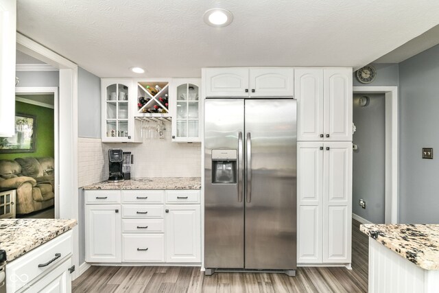 164 Wellington Pkwy, Noblesville, IN 46060 - kitchen featuring stainless steel refrigerator with ice dispenser, light wood-type flooring, white cabinets, glass insert cabinets, and ornamental molding