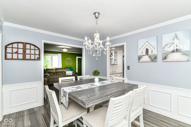 164 Wellington Pkwy, Noblesville, IN 46060 - dining room with ornamental molding, wood finished floors, a chandelier, wainscoting, and a decorative wall