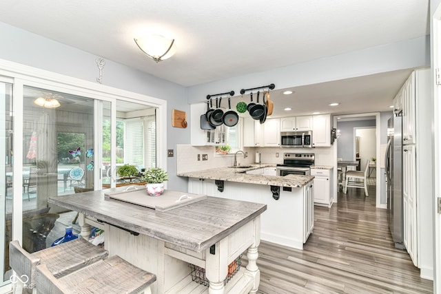 164 Wellington Pkwy, Noblesville, IN 46060 - kitchen with appliances with stainless steel finishes, a peninsula, a sink, light wood finished floors, and white cabinetry
