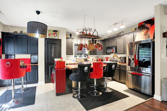 9605 Treyburn Green Way, Indianapolis, IN 46239 - kitchen with stainless steel fridge, black microwave, a kitchen island, light countertops, and a breakfast bar area