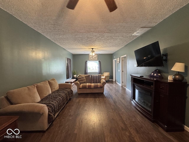 331 E 8th St, Rushville, IN 46173 - living room with a ceiling fan, dark wood-type flooring, a glass covered fireplace, a textured ceiling, and baseboards