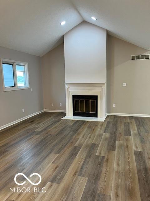 7707 River Rd Unit 10, Indianapolis, IN 46240 - unfurnished living room featuring lofted ceiling, a fireplace with flush hearth, baseboards, wood finished floors, and recessed lighting