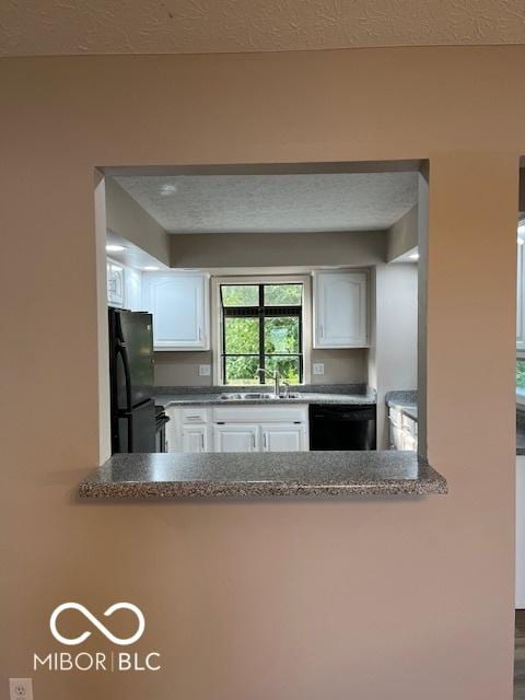 7707 River Rd Unit 10, Indianapolis, IN 46240 - kitchen with black appliances, a sink, white cabinetry, a peninsula, and a textured ceiling