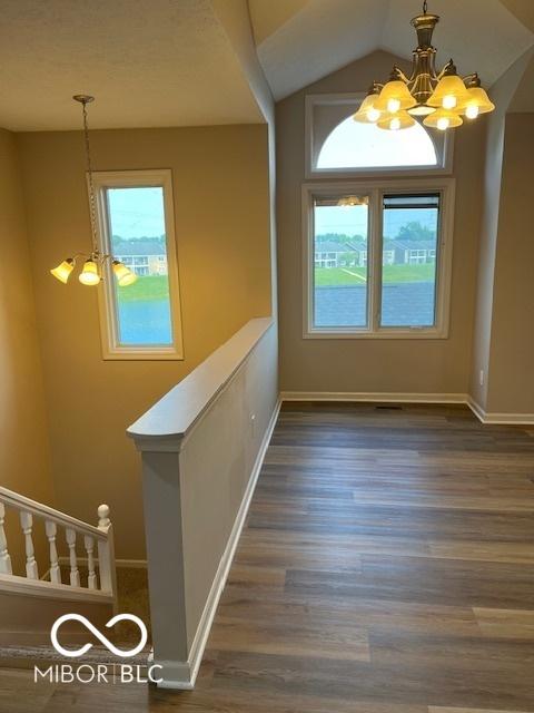 7707 River Rd Unit 10, Indianapolis, IN 46240 - unfurnished dining area featuring a chandelier, wood finished floors, baseboards, and lofted ceiling