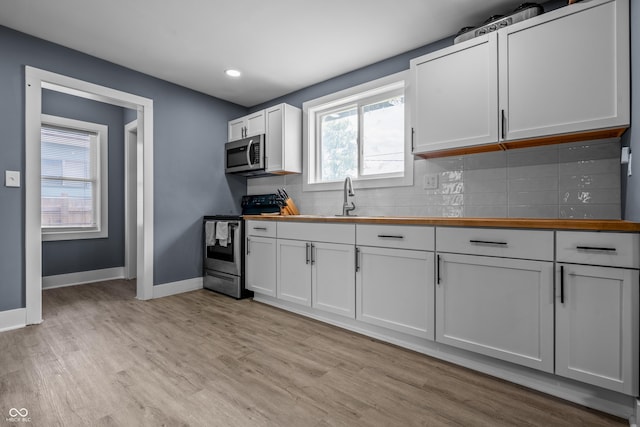 1529 E Tabor St, Indianapolis, IN 46203 - kitchen featuring appliances with stainless steel finishes, light wood finished floors, tasteful backsplash, baseboards, and white cabinetry