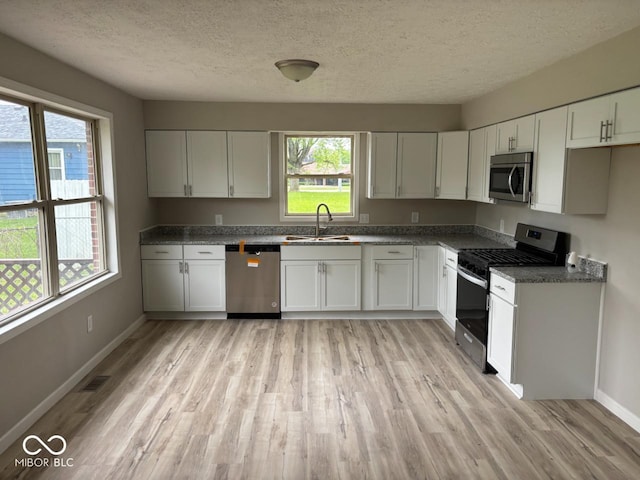 724 Iroquois St, Anderson, IN 46012 - kitchen featuring stainless steel appliances, a sink, healthy amount of natural light, light wood-type flooring, and a textured ceiling