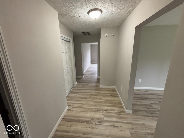 724 Iroquois St, Anderson, IN 46012 - hallway with light wood finished floors, a textured ceiling, and baseboards