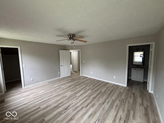 724 Iroquois St, Anderson, IN 46012 - unfurnished bedroom with a textured ceiling, light wood-type flooring, baseboards, a walk in closet, and ensuite bath