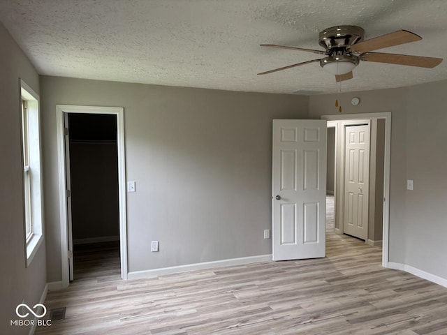 724 Iroquois St, Anderson, IN 46012 - unfurnished bedroom with light wood-style flooring, a textured ceiling, a walk in closet, baseboards, and a closet