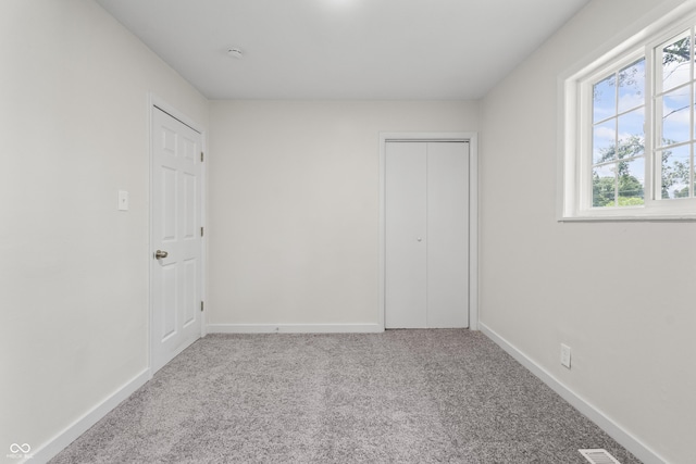 1948 Bloyd Ave, Indianapolis, IN 46218 - unfurnished bedroom featuring multiple windows, carpet floors, and a closet
