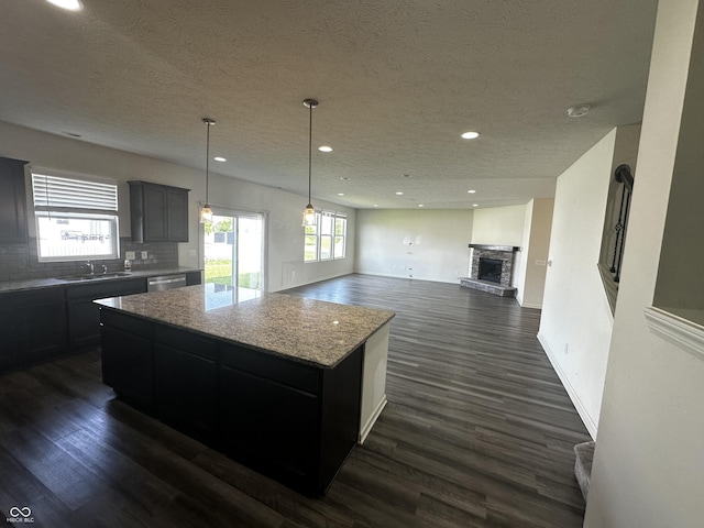 1218 Bedford Dr, Avon, IN 46123 - kitchen featuring a textured ceiling, a center island, dark wood-style floors, decorative backsplash, and light stone countertops