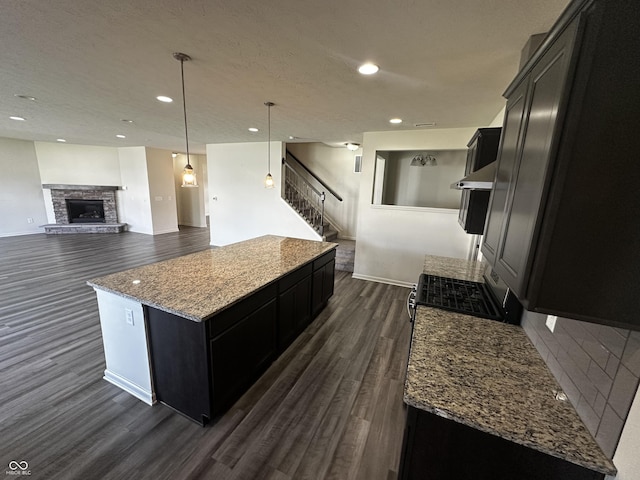 1218 Bedford Dr, Avon, IN 46123 - kitchen featuring dark cabinetry, dark wood-type flooring, a center island, light stone counters, and recessed lighting