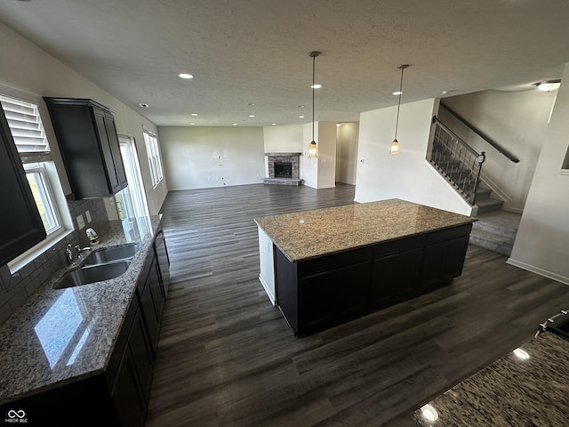 1218 Bedford Dr, Avon, IN 46123 - kitchen with a sink, dark wood-style floors, a stone fireplace, dark cabinets, and recessed lighting