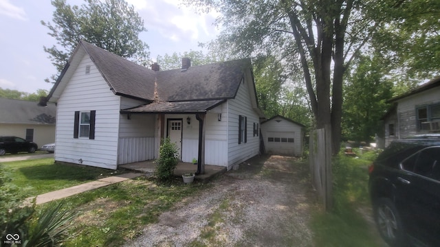 7879 Main St, Coatesville, IN 46121 - view of front facade with a chimney, driveway, an outdoor structure, a garage, and roof with shingles
