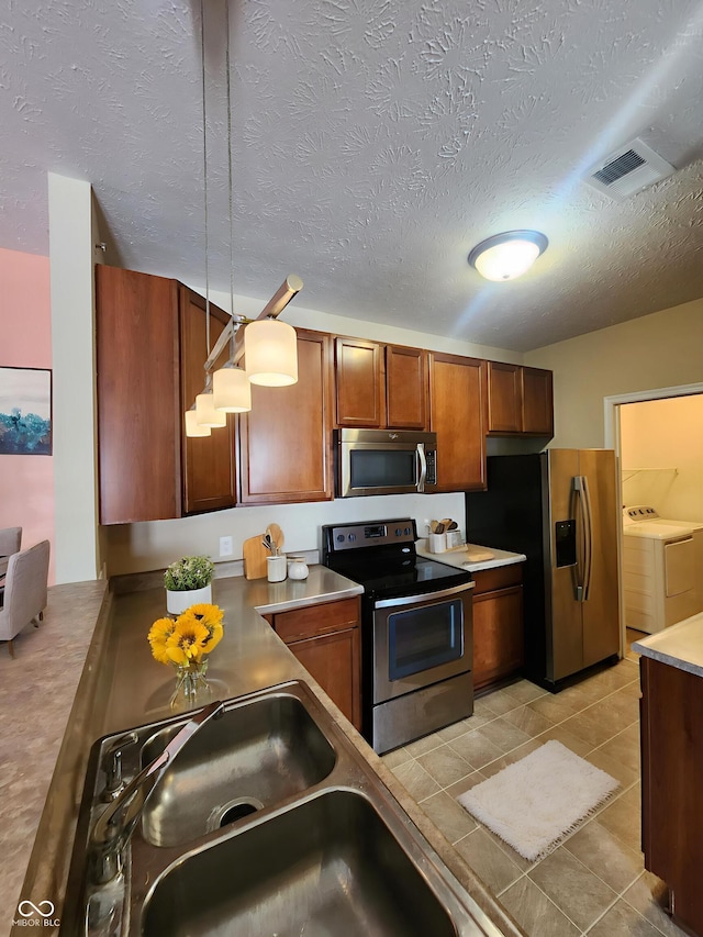 5011 Amber Creek Pl Unit 205, Indianapolis, IN 46237 - kitchen featuring stainless steel appliances, washer and dryer, brown cabinets, a textured ceiling, and a sink