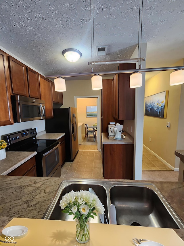 5011 Amber Creek Pl Unit 205, Indianapolis, IN 46237 - kitchen with stainless steel appliances, light tile patterned floors, a textured ceiling, light countertops, and hanging light fixtures